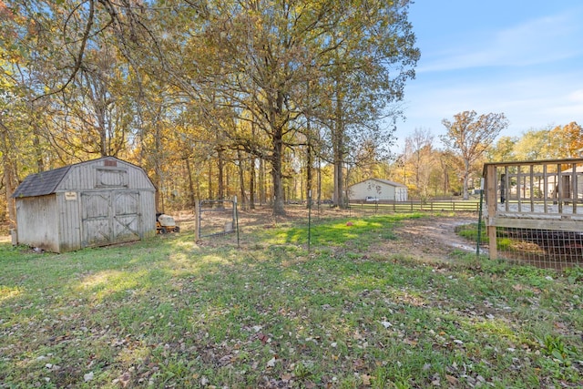 view of yard with an outbuilding, a storage shed, fence, and a deck