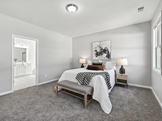 carpeted bedroom with ensuite bathroom, a sink, visible vents, and baseboards