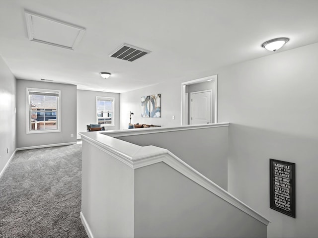 hallway with visible vents, attic access, carpet flooring, an upstairs landing, and baseboards