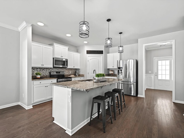 kitchen featuring an island with sink, a kitchen breakfast bar, dark wood-style flooring, stainless steel appliances, and a sink