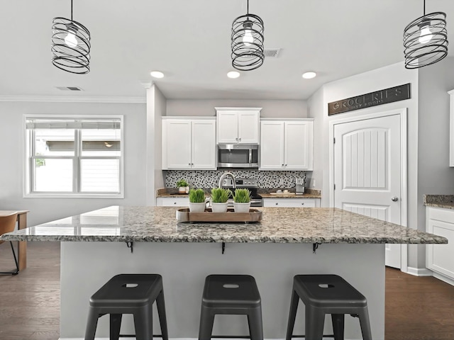 kitchen with dark wood finished floors, tasteful backsplash, appliances with stainless steel finishes, white cabinetry, and a sink