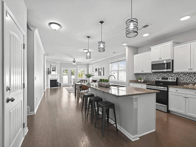 kitchen with stainless steel appliances, a sink, tasteful backsplash, dark wood finished floors, and crown molding