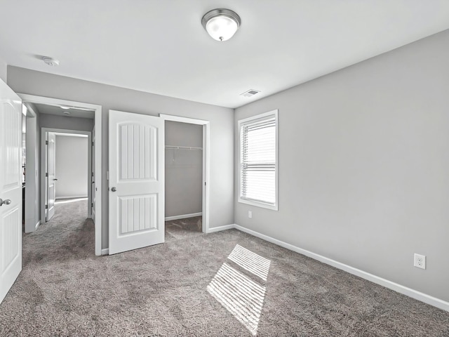 unfurnished bedroom with a closet, carpet flooring, visible vents, and baseboards