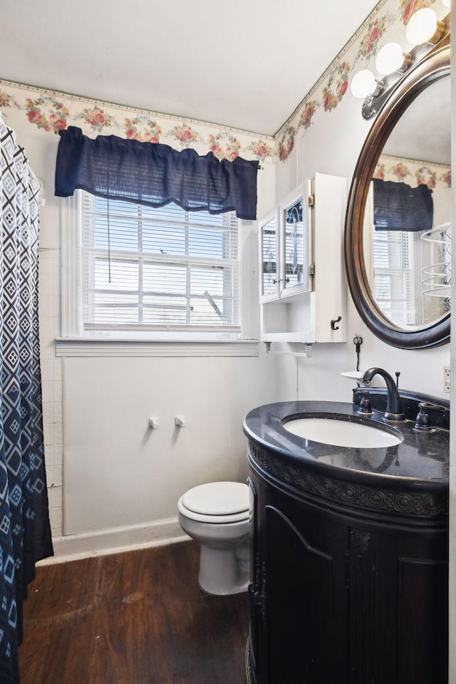 bathroom with a shower with shower curtain, toilet, vanity, wood finished floors, and baseboards