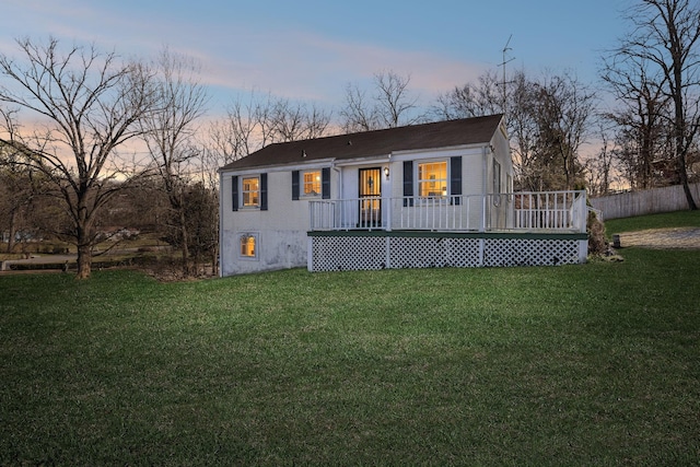 back of property at dusk featuring a lawn and fence