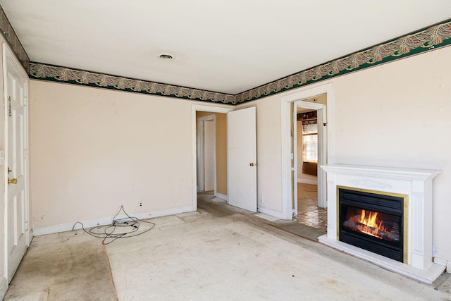 unfurnished living room with a glass covered fireplace and baseboards