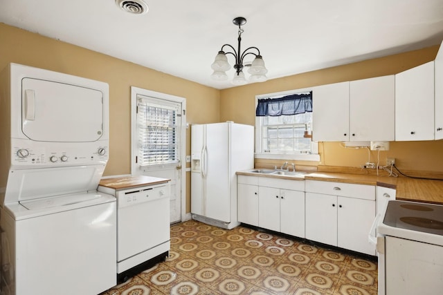 clothes washing area featuring a notable chandelier, stacked washer and dryer, visible vents, a sink, and laundry area