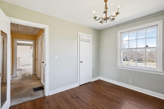 unfurnished bedroom with a closet, visible vents, attic access, wood finished floors, and baseboards