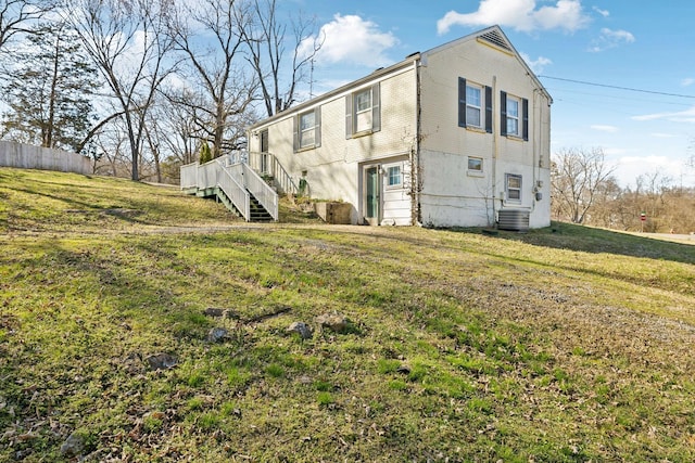 exterior space with central air condition unit, a yard, stairway, and fence