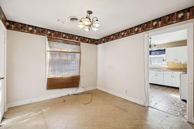 unfurnished dining area featuring visible vents, a notable chandelier, a sink, and baseboards