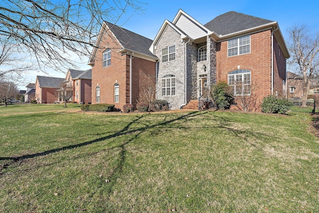 traditional-style house with a front yard, stone siding, brick siding, and fence