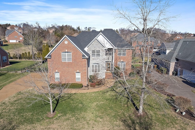 rear view of property featuring stone siding, a yard, fence, and brick siding