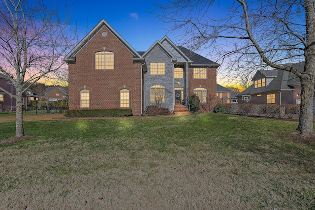 view of front of house featuring a yard, stone siding, and brick siding