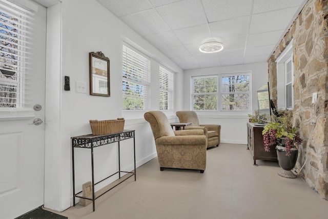 sitting room with finished concrete floors and a drop ceiling