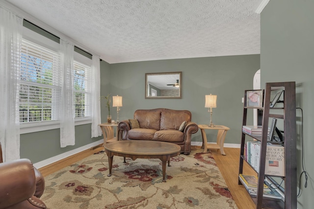 living room featuring a textured ceiling, baseboards, and wood finished floors