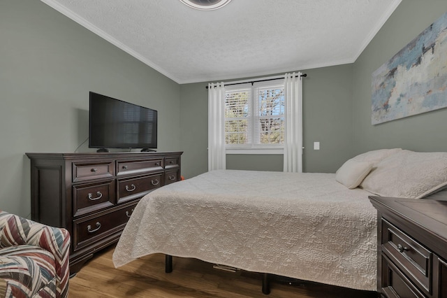 bedroom featuring a textured ceiling, wood finished floors, and crown molding