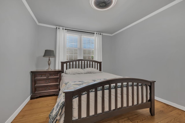 bedroom with crown molding, baseboards, and wood finished floors