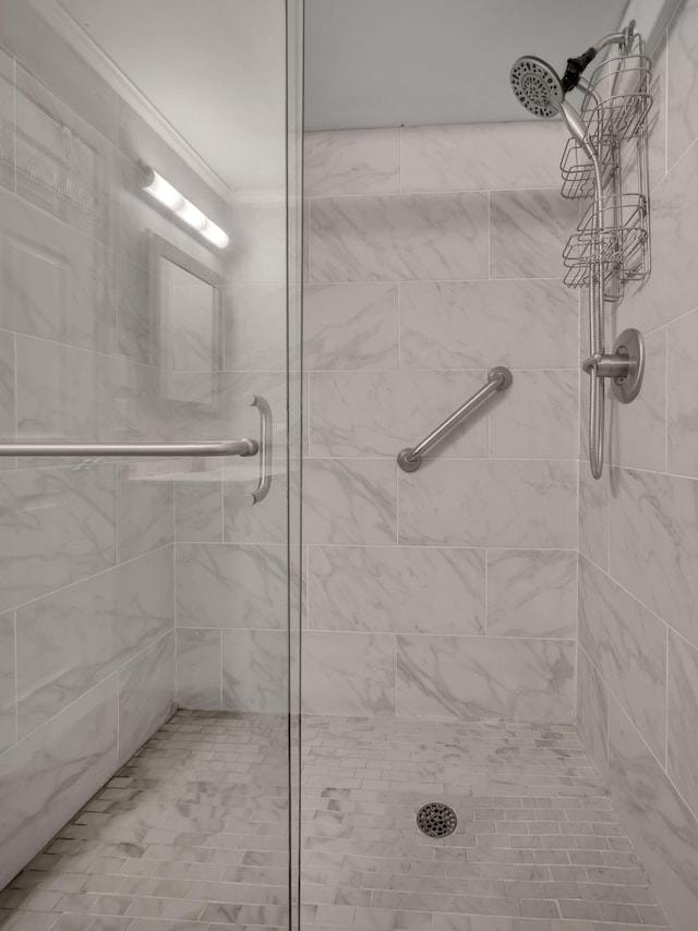 bathroom with a tile shower and crown molding