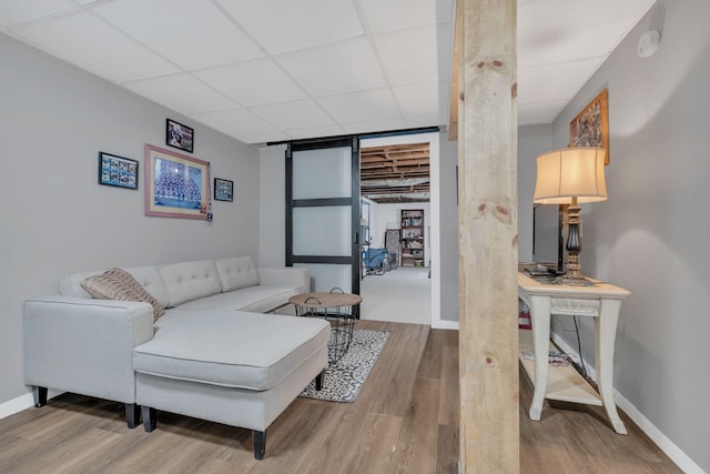 living room featuring a drop ceiling, wood finished floors, and baseboards