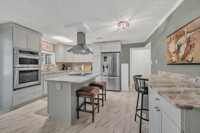 kitchen featuring a kitchen breakfast bar, stainless steel appliances, light stone countertops, and island range hood