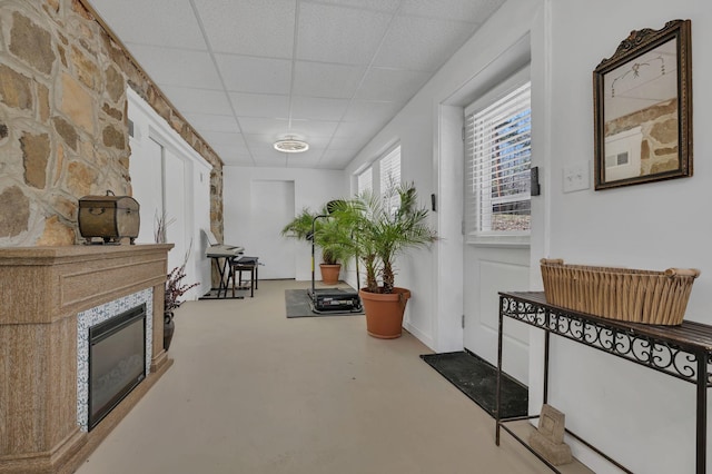 interior space with a large fireplace, finished concrete floors, and a drop ceiling