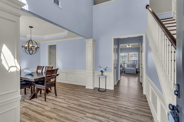 dining space with light wood-style flooring, visible vents, stairs, a tray ceiling, and crown molding