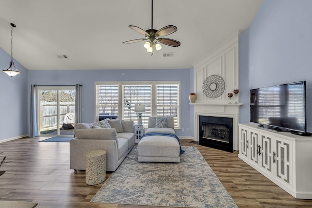 living room with visible vents, ceiling fan, wood finished floors, vaulted ceiling, and a fireplace