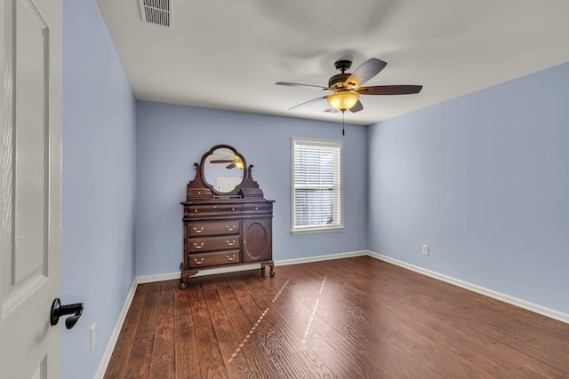 spare room featuring ceiling fan, dark wood finished floors, visible vents, and baseboards