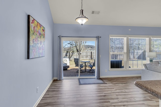 doorway featuring a healthy amount of sunlight, baseboards, visible vents, and wood finished floors