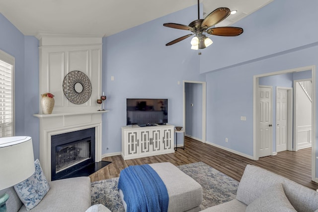 living room with a fireplace with flush hearth, ceiling fan, wood finished floors, and baseboards