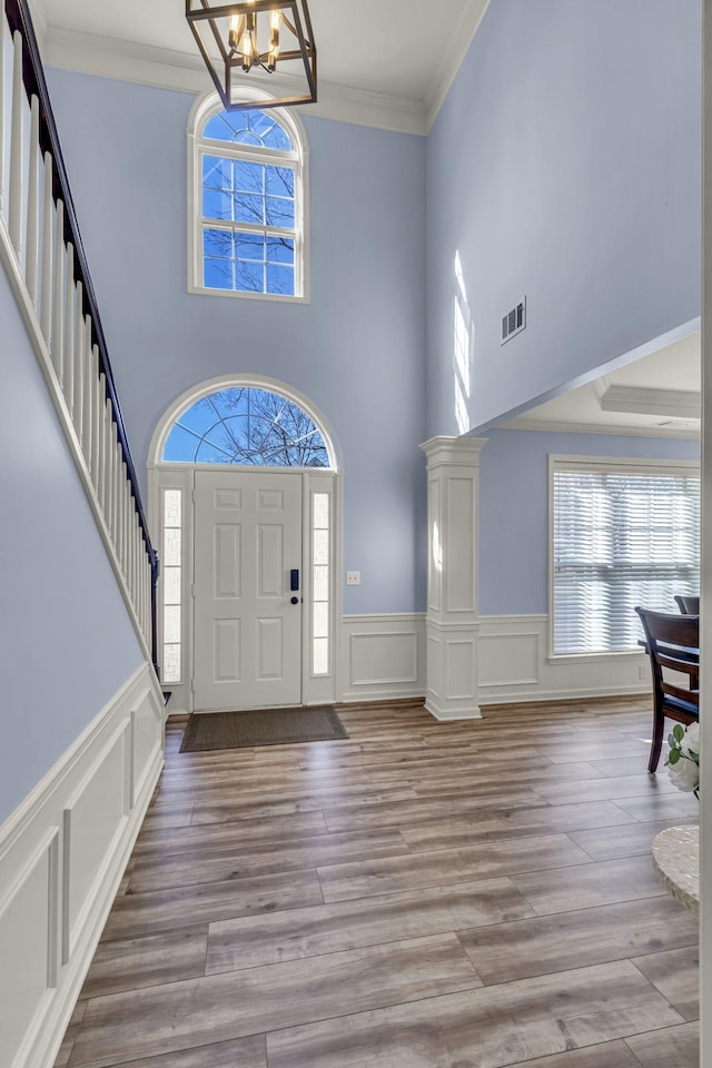 foyer entrance with visible vents, wood finished floors, stairs, crown molding, and a notable chandelier