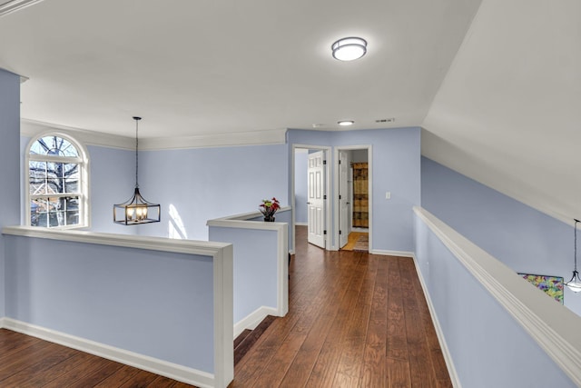 corridor with a chandelier, hardwood / wood-style flooring, visible vents, an upstairs landing, and baseboards