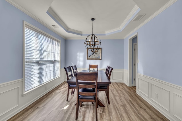 dining space featuring an inviting chandelier, light wood-style flooring, visible vents, and a raised ceiling