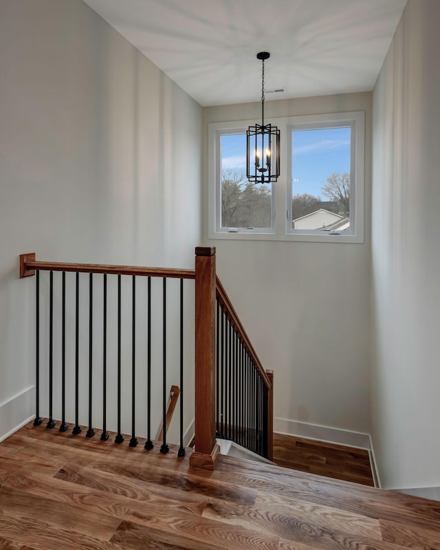 stairs featuring a chandelier, wood finished floors, and baseboards