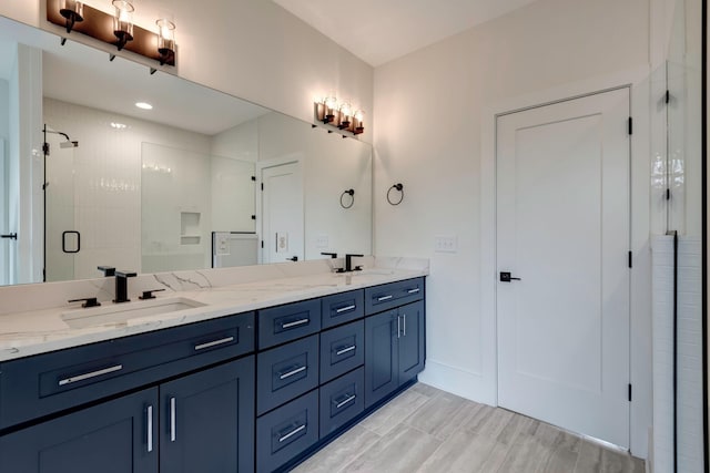 bathroom with double vanity, a stall shower, baseboards, and a sink