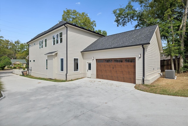 view of home's exterior featuring a garage, concrete driveway, a shingled roof, and central air condition unit