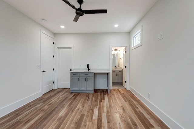 interior space with recessed lighting, light wood-style flooring, a ceiling fan, a sink, and baseboards