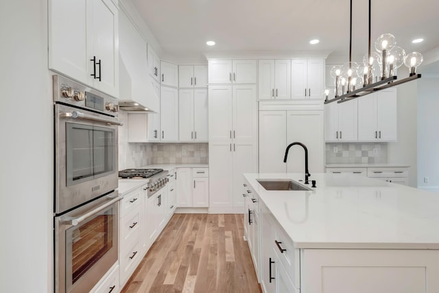 kitchen with stainless steel appliances, a sink, light countertops, and light wood-style floors