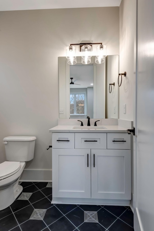 bathroom with ceiling fan, toilet, vanity, baseboards, and tile patterned floors