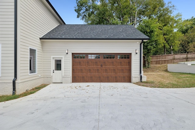 garage with concrete driveway and fence