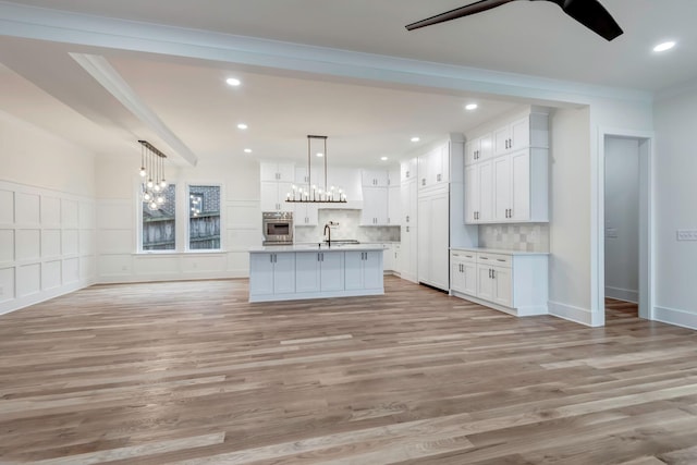 kitchen featuring open floor plan, ceiling fan with notable chandelier, stainless steel oven, and white cabinets