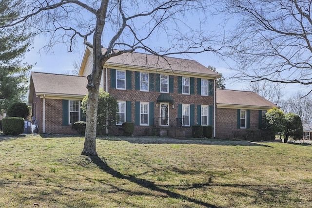 colonial inspired home with a front yard and brick siding