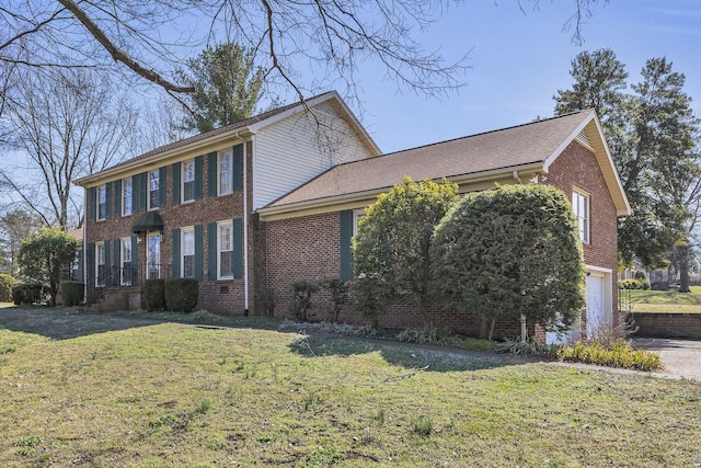 view of front facade featuring an attached garage, a front lawn, and brick siding