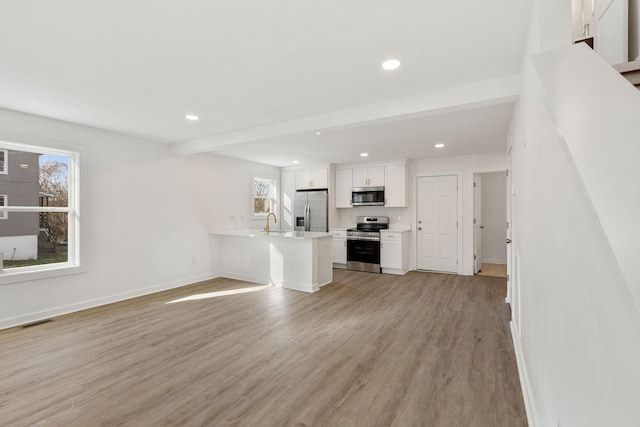 unfurnished living room with a healthy amount of sunlight, light wood-type flooring, visible vents, and baseboards