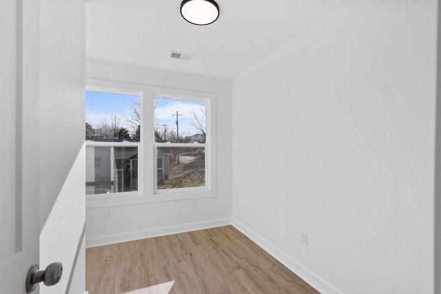 empty room with visible vents, baseboards, and wood finished floors