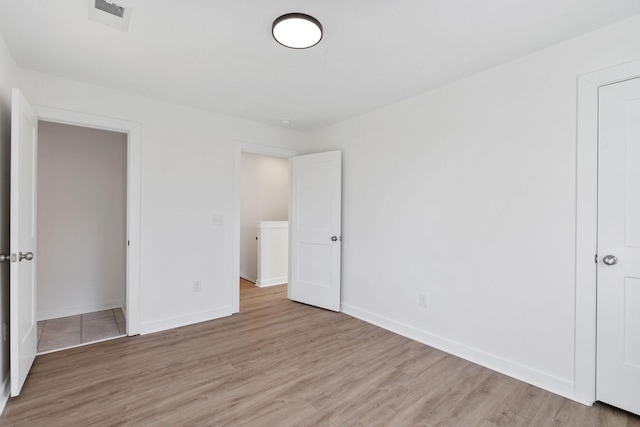 unfurnished bedroom with light wood-style flooring, visible vents, and baseboards