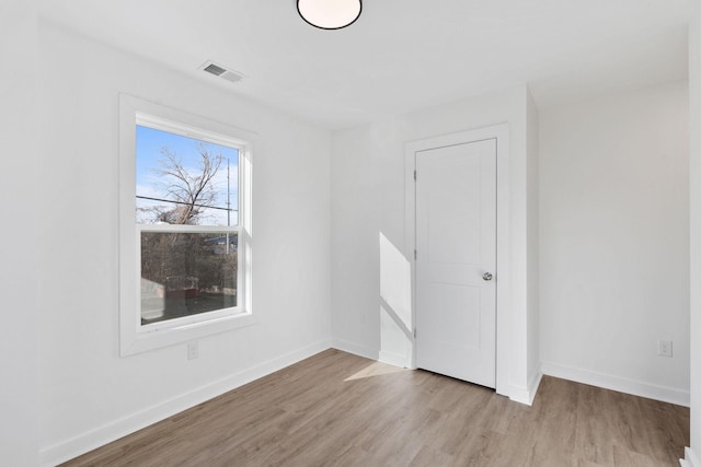 empty room with visible vents, baseboards, and wood finished floors