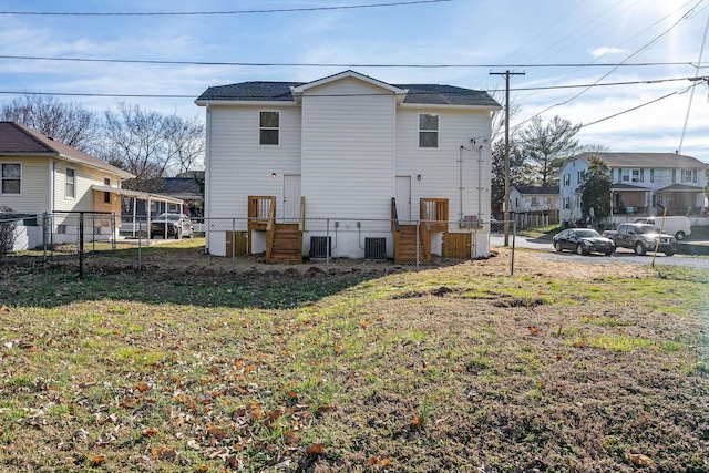 rear view of house featuring a yard, fence, and central air condition unit