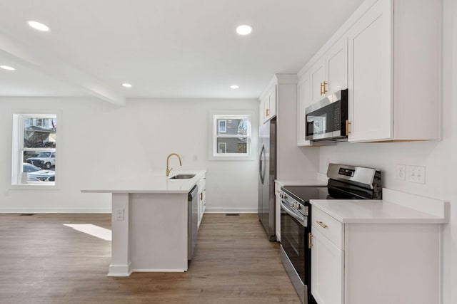 kitchen with stainless steel appliances, white cabinets, a healthy amount of sunlight, and a sink