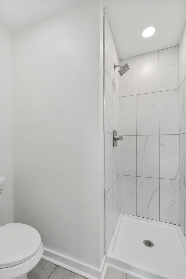 bathroom with a stall shower, toilet, and baseboards